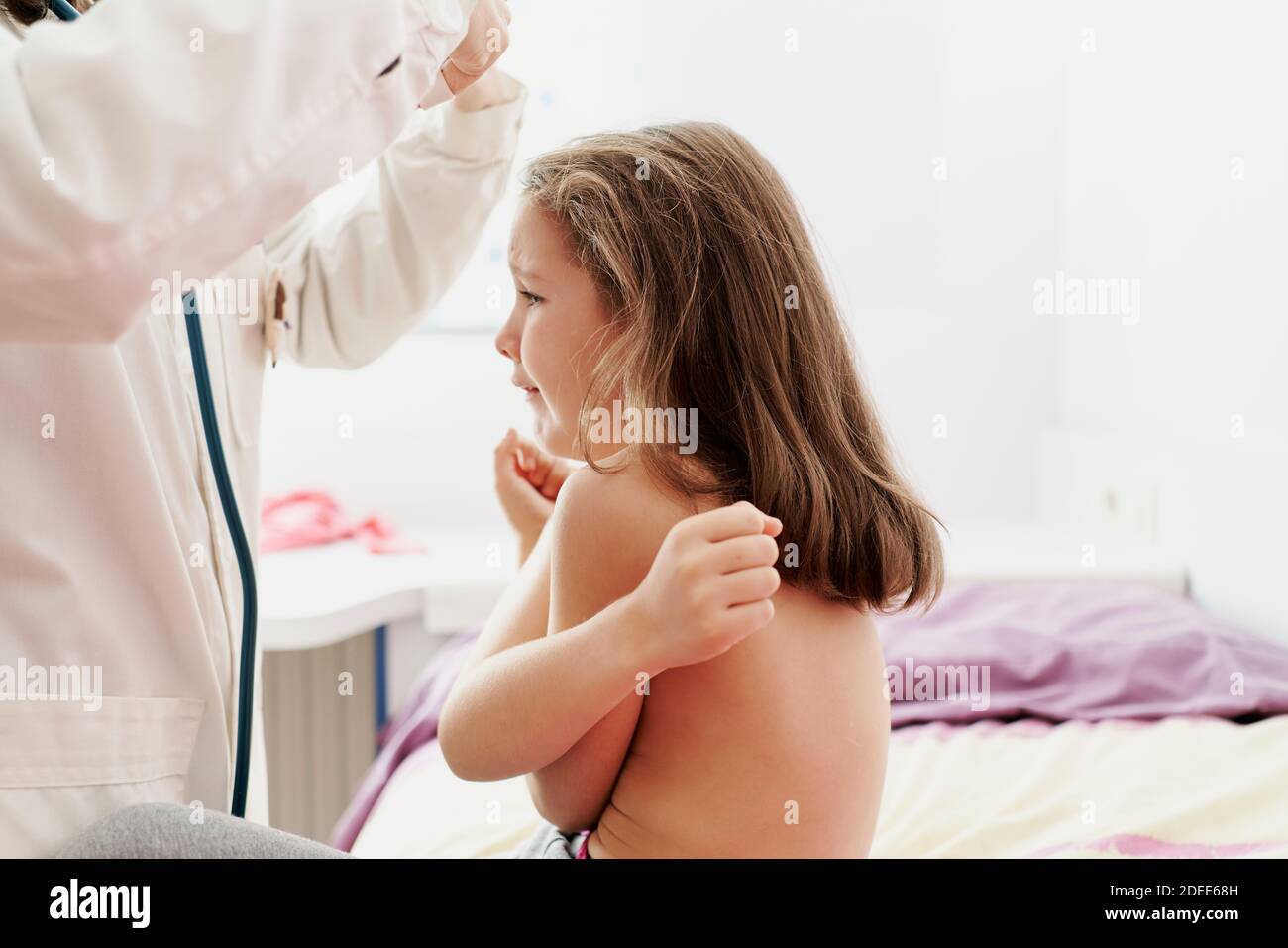Girl with a sad, tearful face while being examined by a doctor. Concept of a family doctor Stock Photo