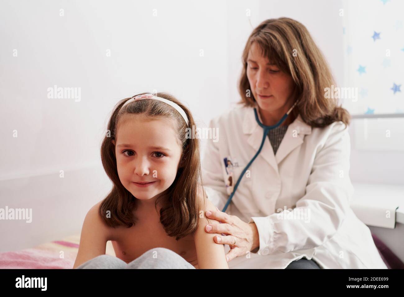 Pediatric doctor examine little happy girl with stethoscope. Child