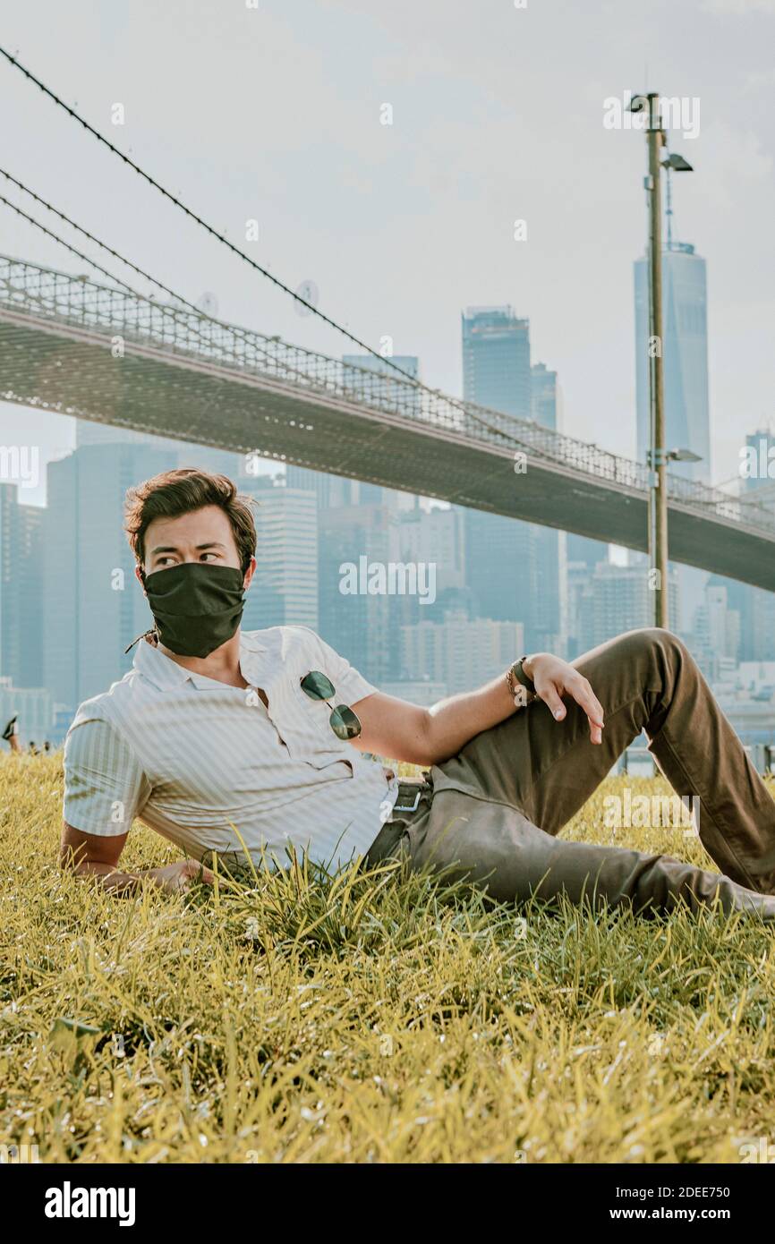 Young man sitting in park wearing face mask Stock Photo - Alamy
