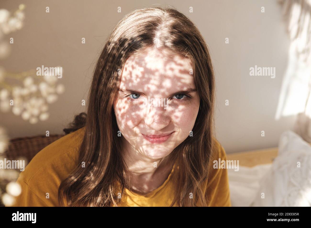Portrait of young beautiful woman by the window with shadow from ...