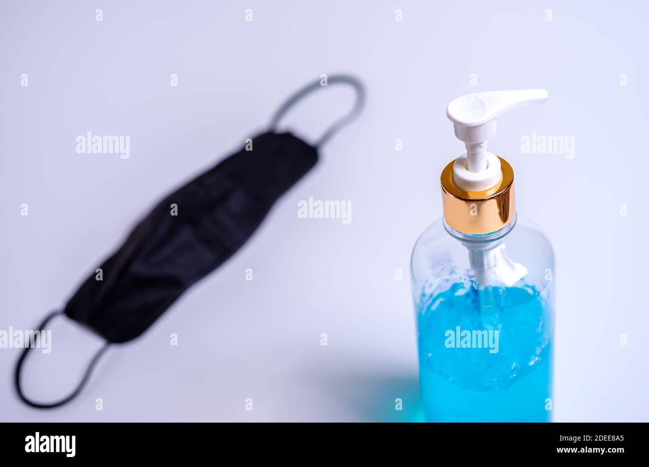 Alcohol gel with mask on blurred white background, Corona virus or covid-19 concept Stock Photo