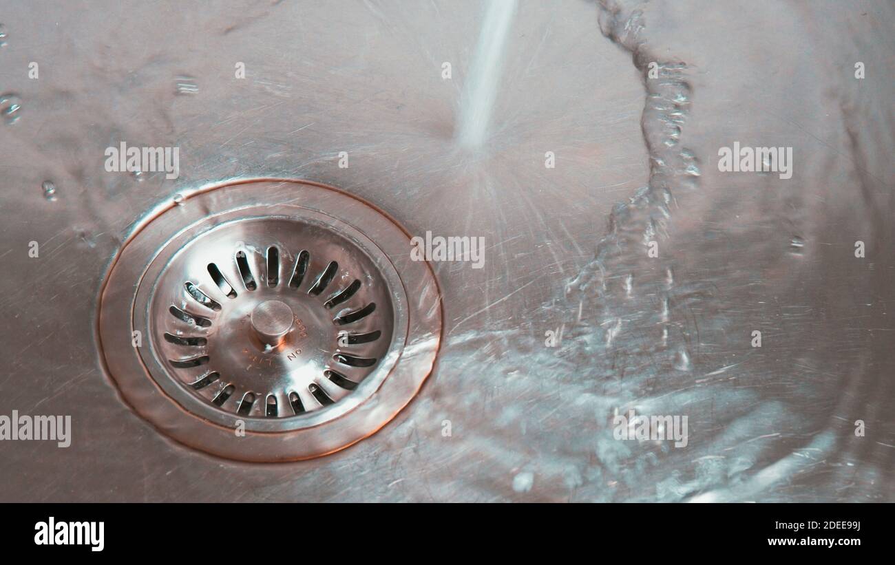 Metal sink with water going down drain. Close up Stock Photo Alamy