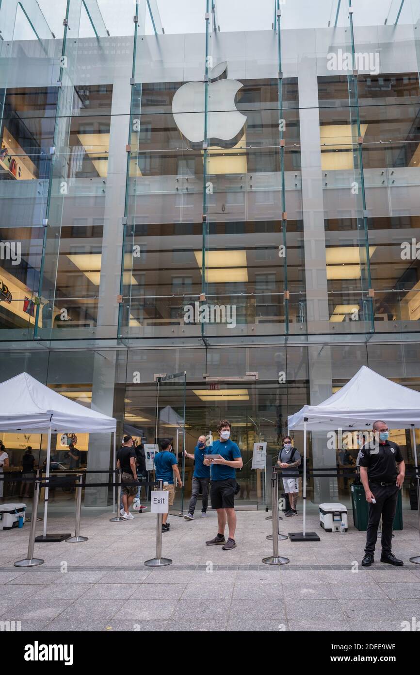 People wearing masks in front of the Apple store. Stock Photo
