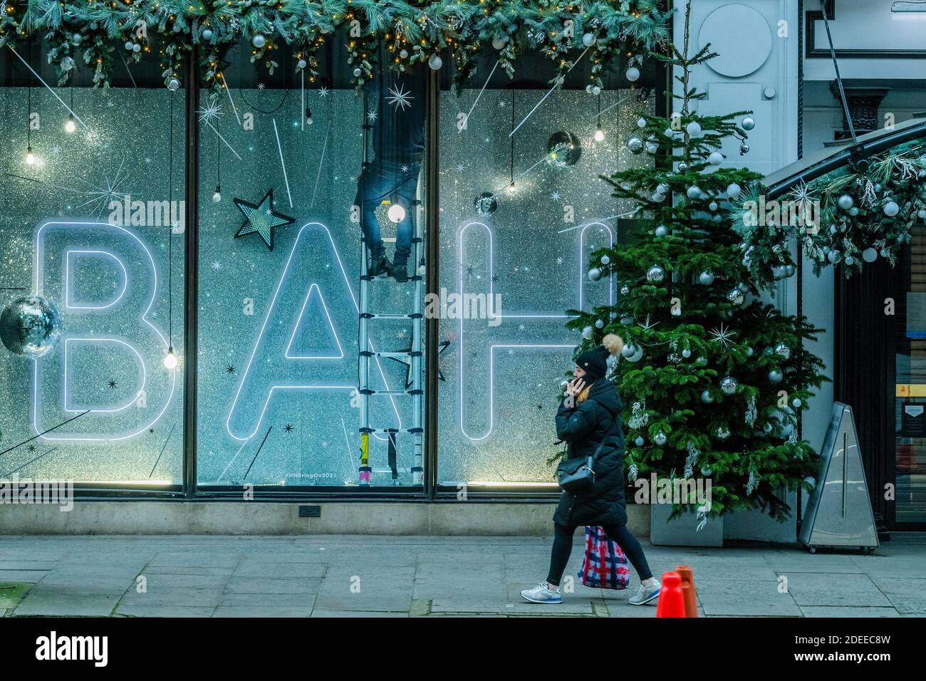 London, UK. 30th Nov, 2020. Harvey Nichols makes final adjustments to its window messages - Bah Humbug and Bring on 2021. Closed retailers do their best to promote Christmas sales. People are still out in central london, and prepare to re-open as the second lockdown nears its end. The Christmas lights are on but the shops are shut. Many people wear masks, even outside. Credit: Guy Bell/Alamy Live News Stock Photo