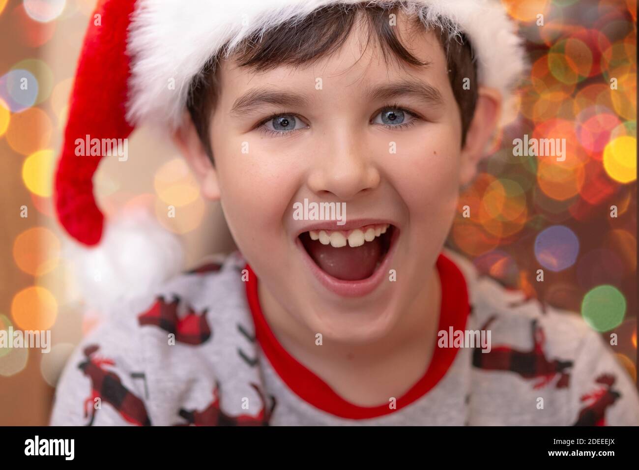 Close-up portrait of a handsome joyful European boy in a red Santa Claus cap Stock Photo