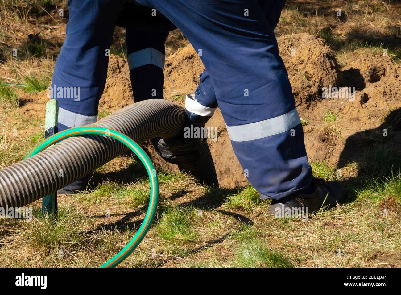 https://c8.alamy.com/comp/2DEEJAP/man-worker-holding-pipe-providing-sewer-cleaning-service-outdoor-sewage-pumping-machine-is-unclogging-blocked-manhole-2DEEJAP.jpg