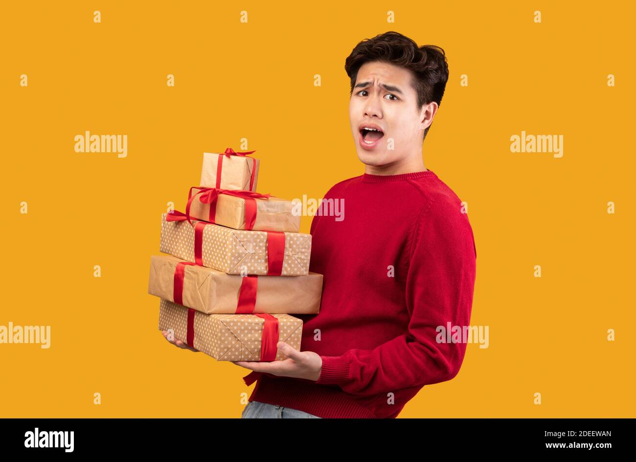 Excited asian guy holding stack of present boxes Stock Photo - Alamy