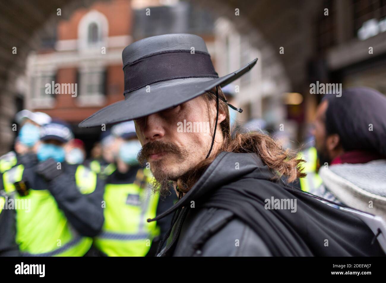 Anti-lockdown protest, Regent Street, London, 28 November 2020. A protester in Guy Fawkes costume stands in front of a line of police officers. Stock Photo