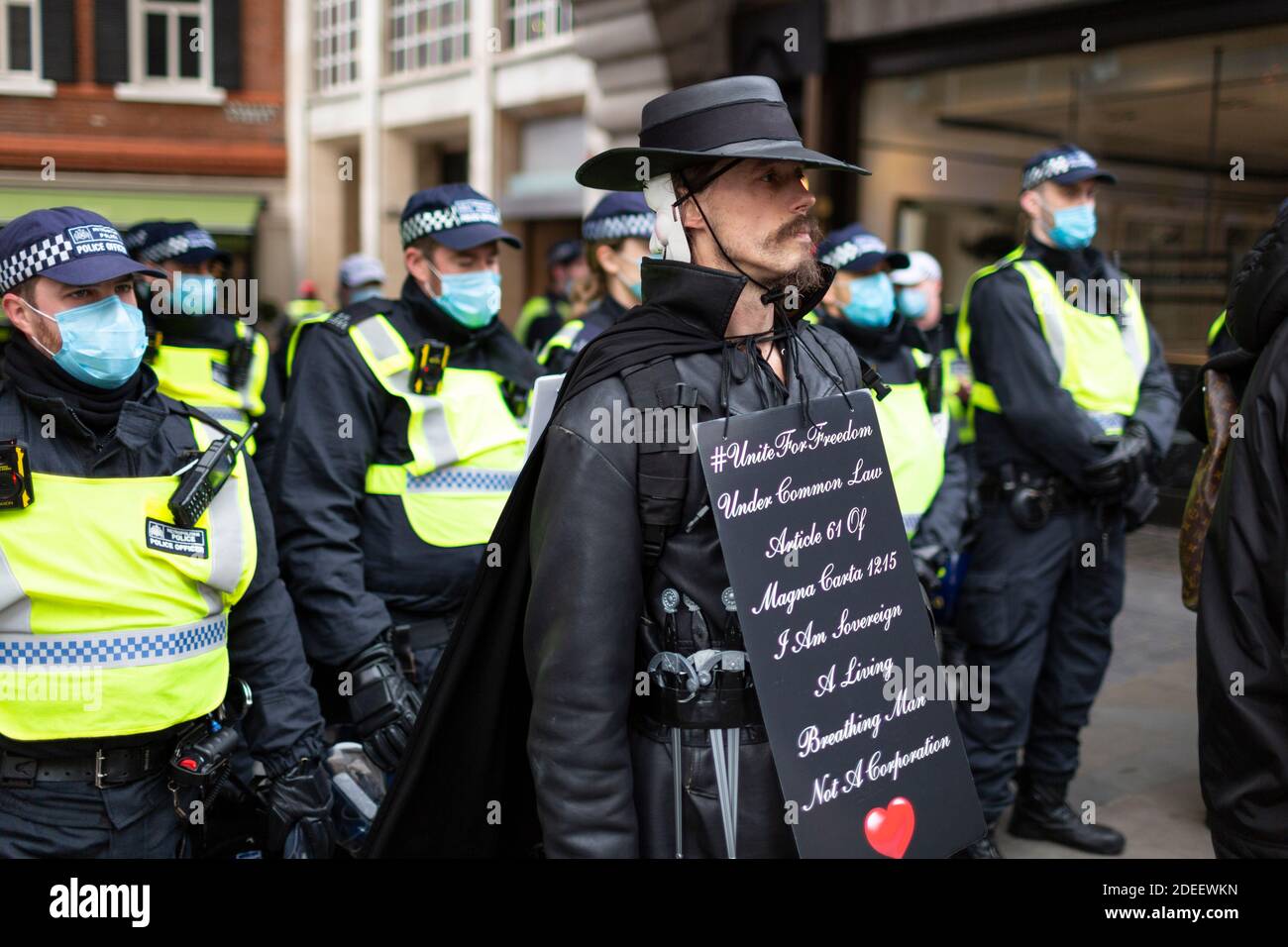 Anti-lockdown protest, Regent Street, London, 28 November 2020. A protester in Guy Fawkes costume stands in front of a line of police officers. Stock Photo