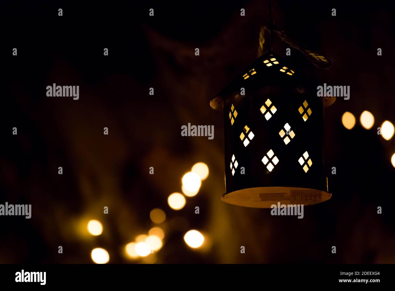 A lit lantern hanging on a tree branch during a dark winter night. Glowing light. Festival of light. Stock Photo