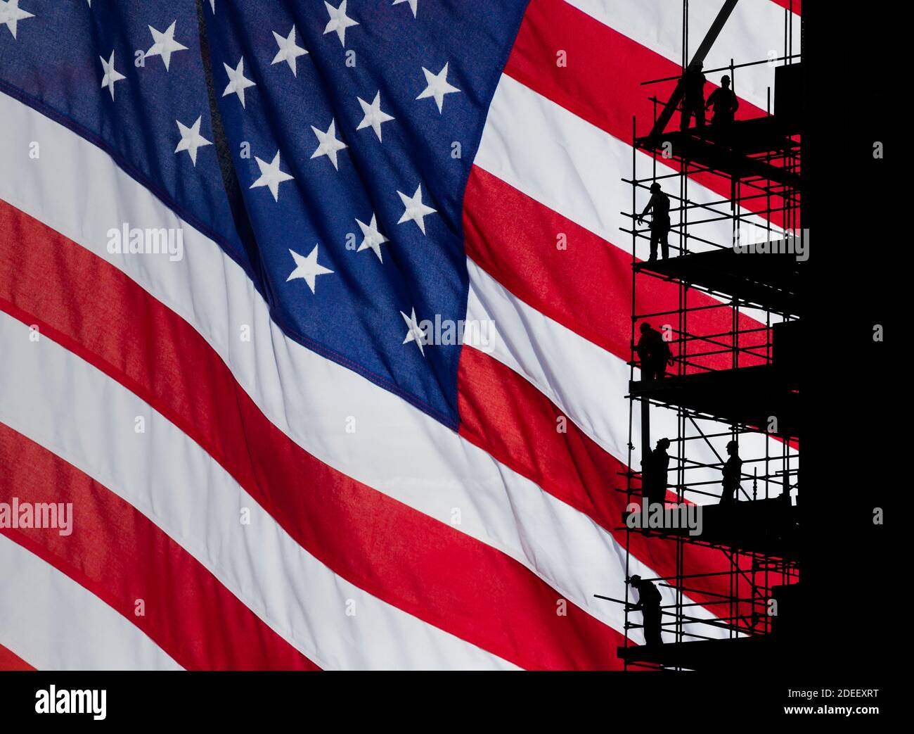 Construction workers on scaffolding with Stars and Stripes flag as backdrop. Concept image: USA, American economy, blue collar worker... Stock Photo