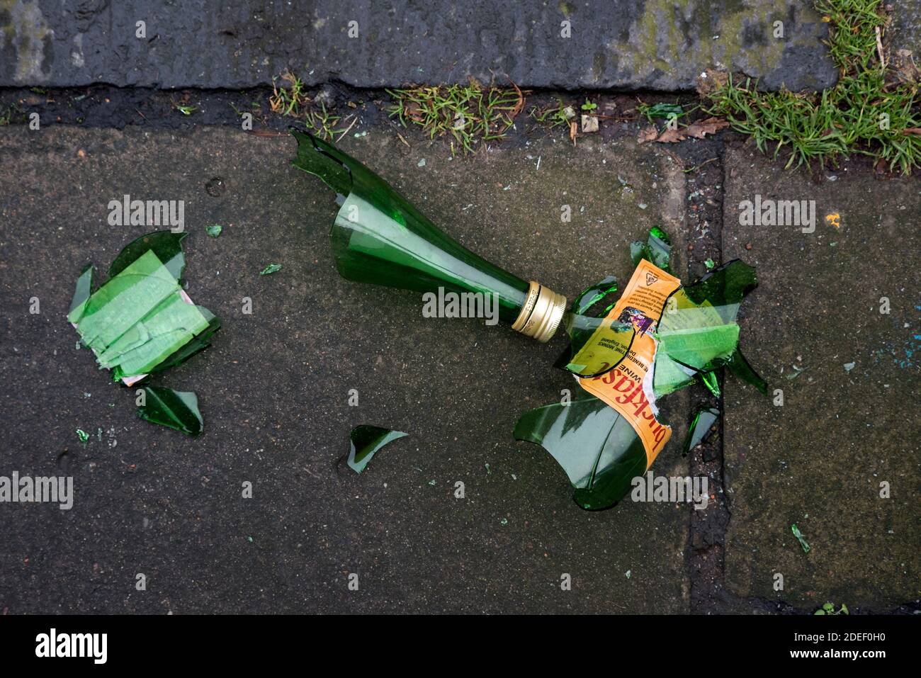 A bottle of Buckfast Tonic Wine, or 'Buckie' as it is known locally, lies broken on the pavement. Stock Photo