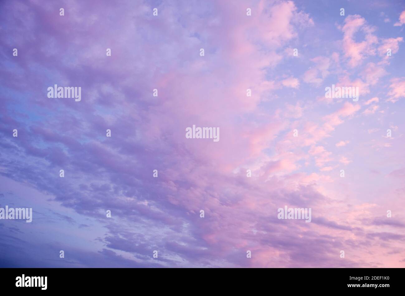 Beautiful blue sky background. Soft white clouds at sunset. Many pink, magenta and orange tones and patterns of clouds. Stock Photo