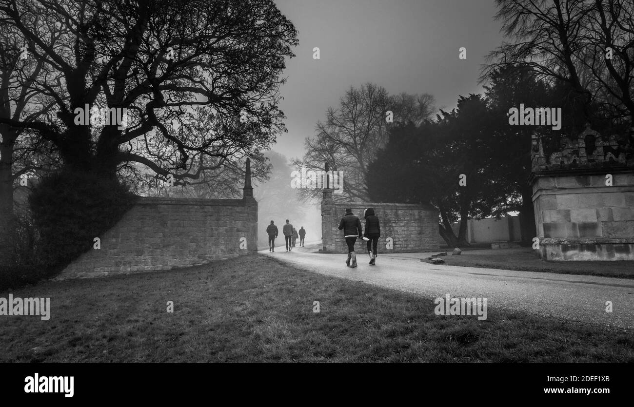 People walking along a small country road on a late foggy evening in front of Hardwick Hall, Derbyshire. Stock Photo