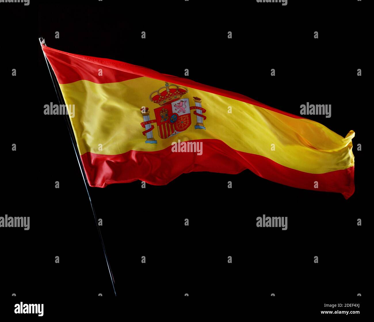 Spanish flag blowing in the wind isolated against a black background, studio shot. Stock Photo
