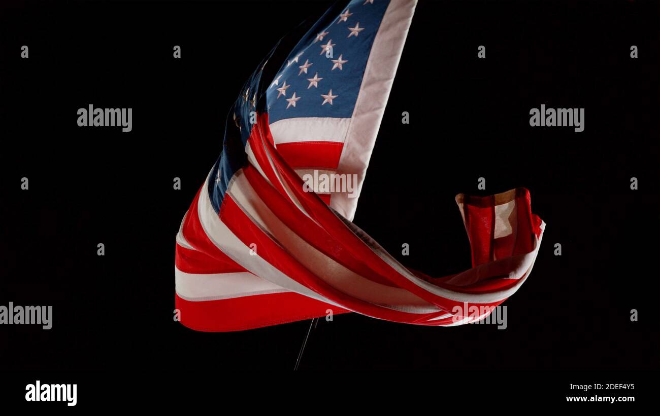 American flag blowing in the wind isolated against a black background. Symbol of North America Stock Photo