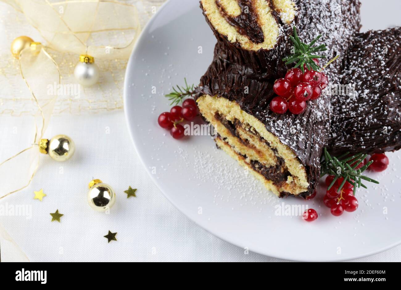 Chocolate Christmas Yule Log, Buche de Noel on white background. Christmas decorations. Stock Photo