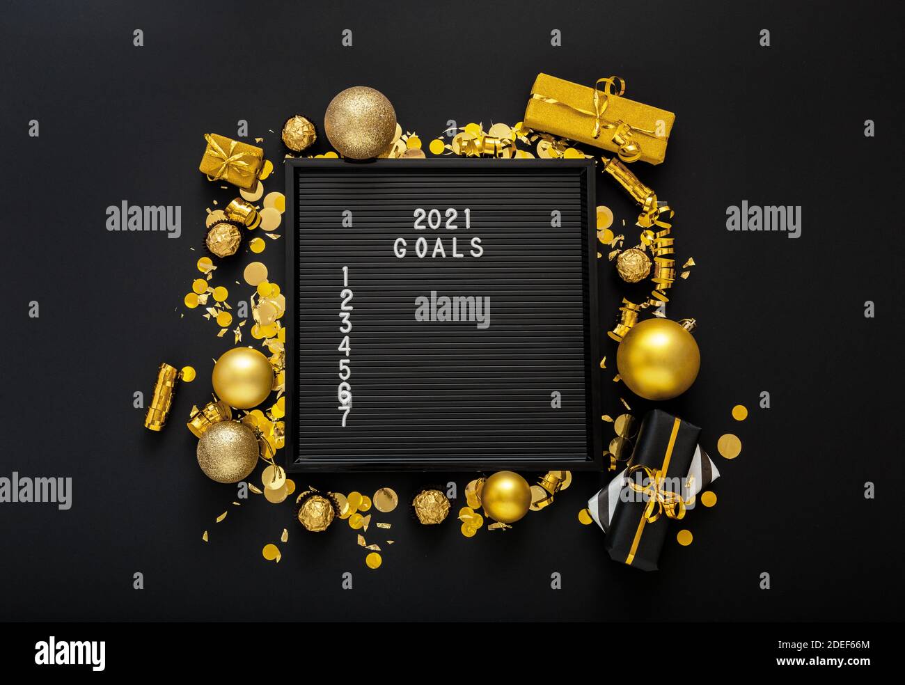 Numbered list of 2021 Goals on black Board in frame made of gold festive decor gift boxes confetti. New year eve 2021 goals, resolution check list Stock Photo