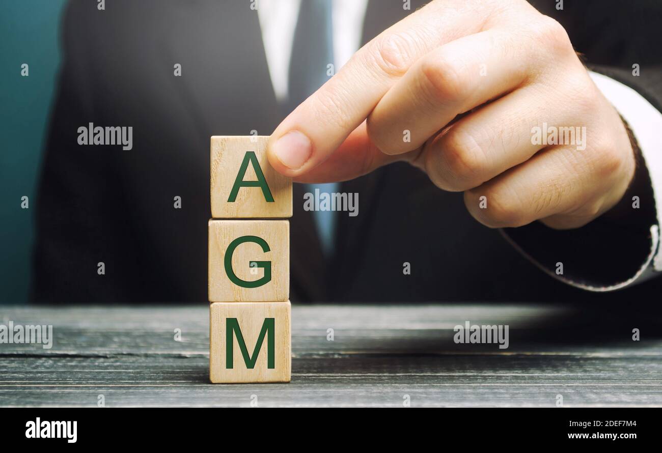 Wooden blocks with the word AGM - Annual general meeting. Mandatory yearly gathering of a company's interested shareholders. Annual report. Company's Stock Photo