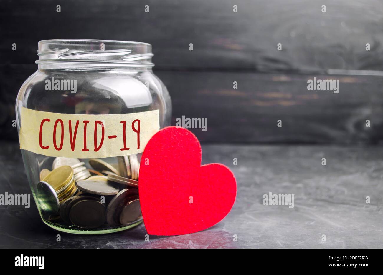 Glass jar with the inscription Covid-19 and a heart. Coronavirus pandemic infection. Healthcare, medicine concept. Ambulance. Patient finance concept. Stock Photo