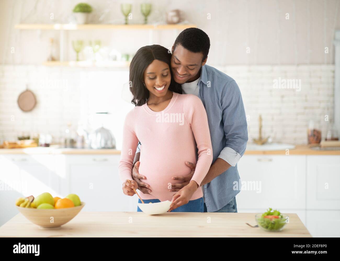 Lovely black pregnant woman making healthy breakfast in kitchen and