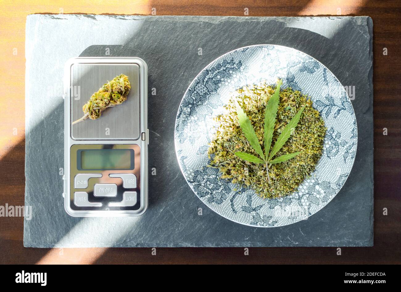 Tray with marijuana and digital scale with cannabis bud. Top view of wooden  table with sun rays Stock Photo - Alamy