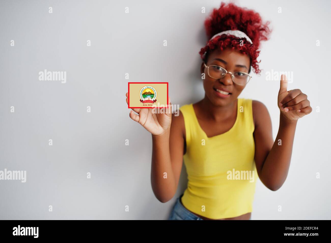 African woman with afro hair hold Ekiti flag isolated on white background, show thumb up. States of Nigeria concept. Stock Photo