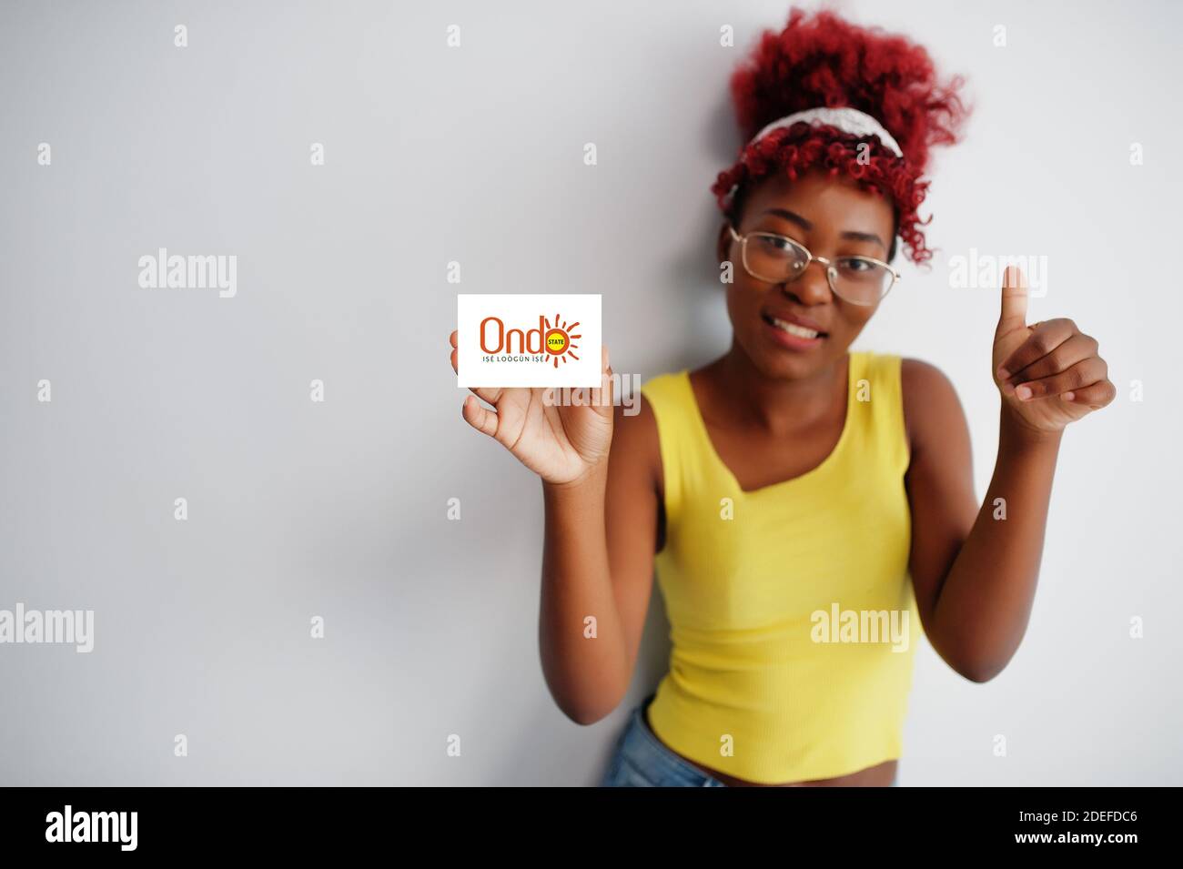 African woman with afro hair hold Ondo flag isolated on white background, show thumb up. States of Nigeria concept. Stock Photo