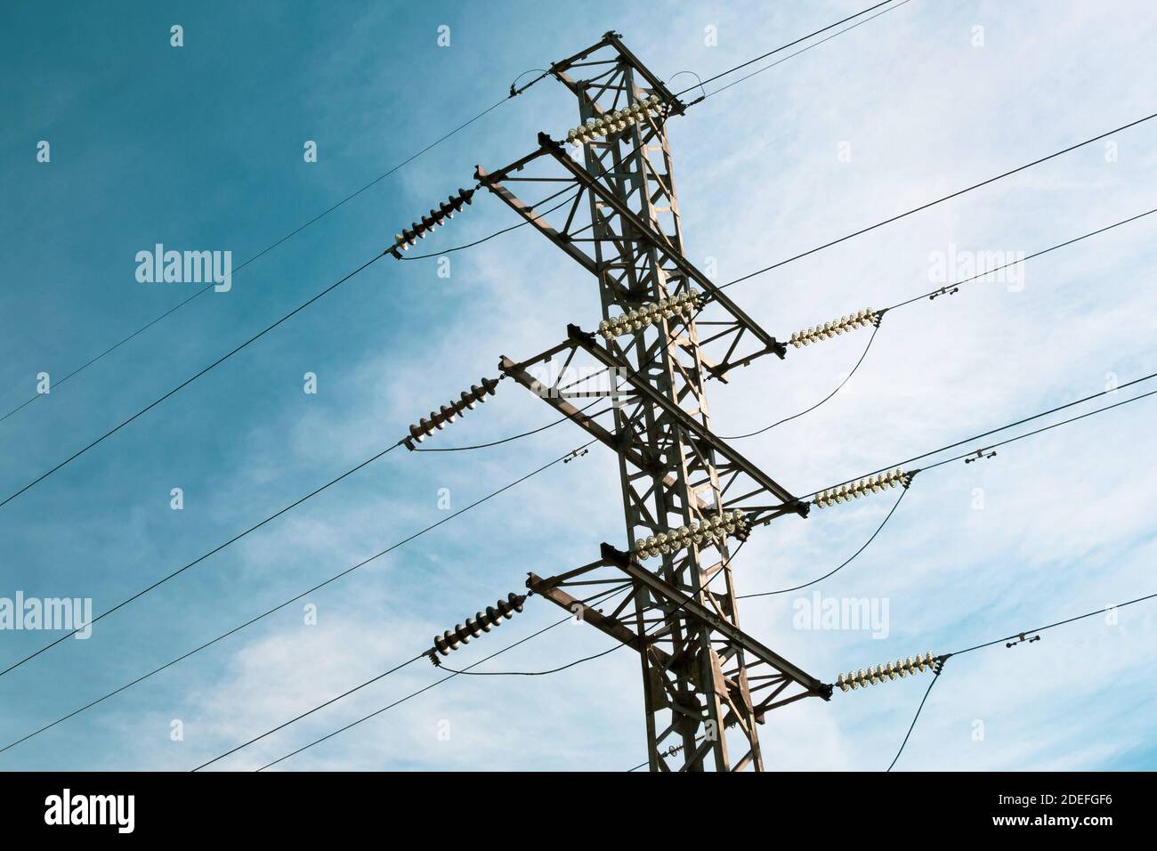 Energy distribution high voltage power line tower with wires and trees Stock Photo