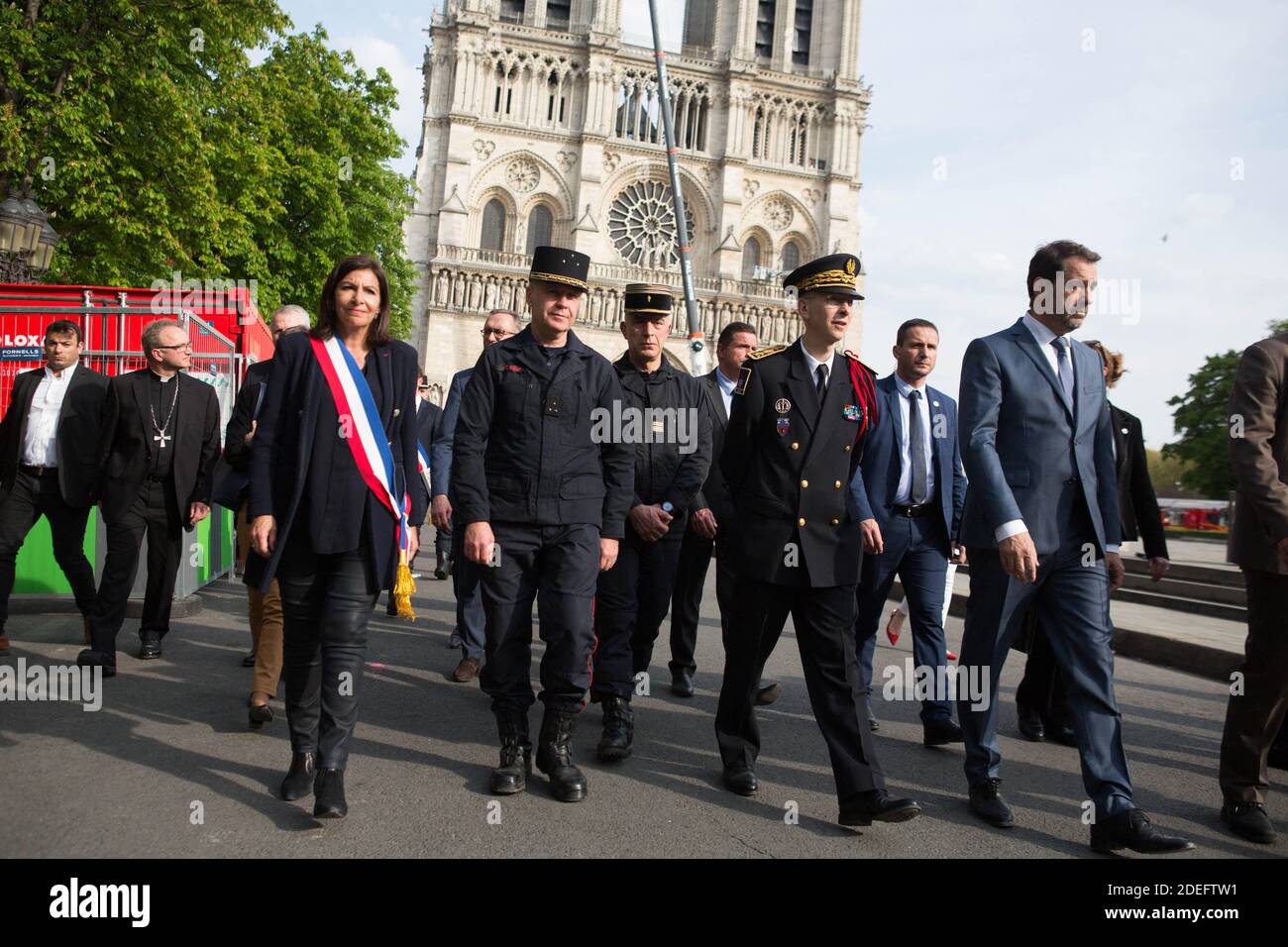 French Interior Minister Christophe Castaner (R), Paris prefect Didier Lallement (2R), Paris mayor Anne Hidalgo (L), and other officials walk by Notre Dame cathedral on April 18, 2019 in Paris. France paid a daylong tribute on April 18, 2019 to the Paris firefighters who saved Notre Dame Cathedral from collapse, while construction workers rushed to secure an area above one of the church's famed rose-shaped windows and other vulnerable sections of the fire-damaged landmark. Photo by Raphael Lafargue/ABACAPRESS.COM Stock Photo