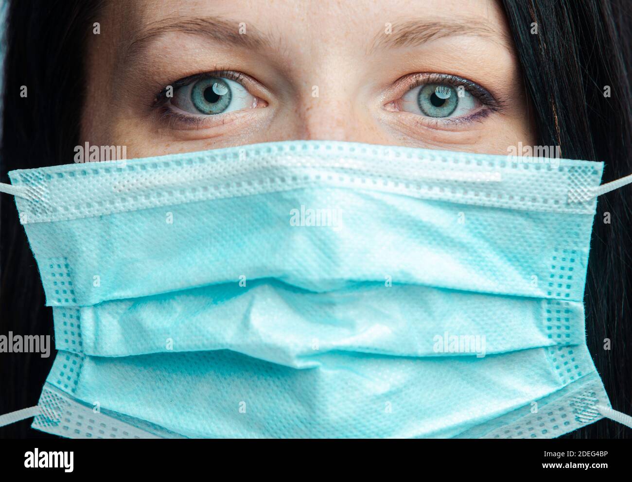 Woman with blue eyes puts a medical mask Stock Photo