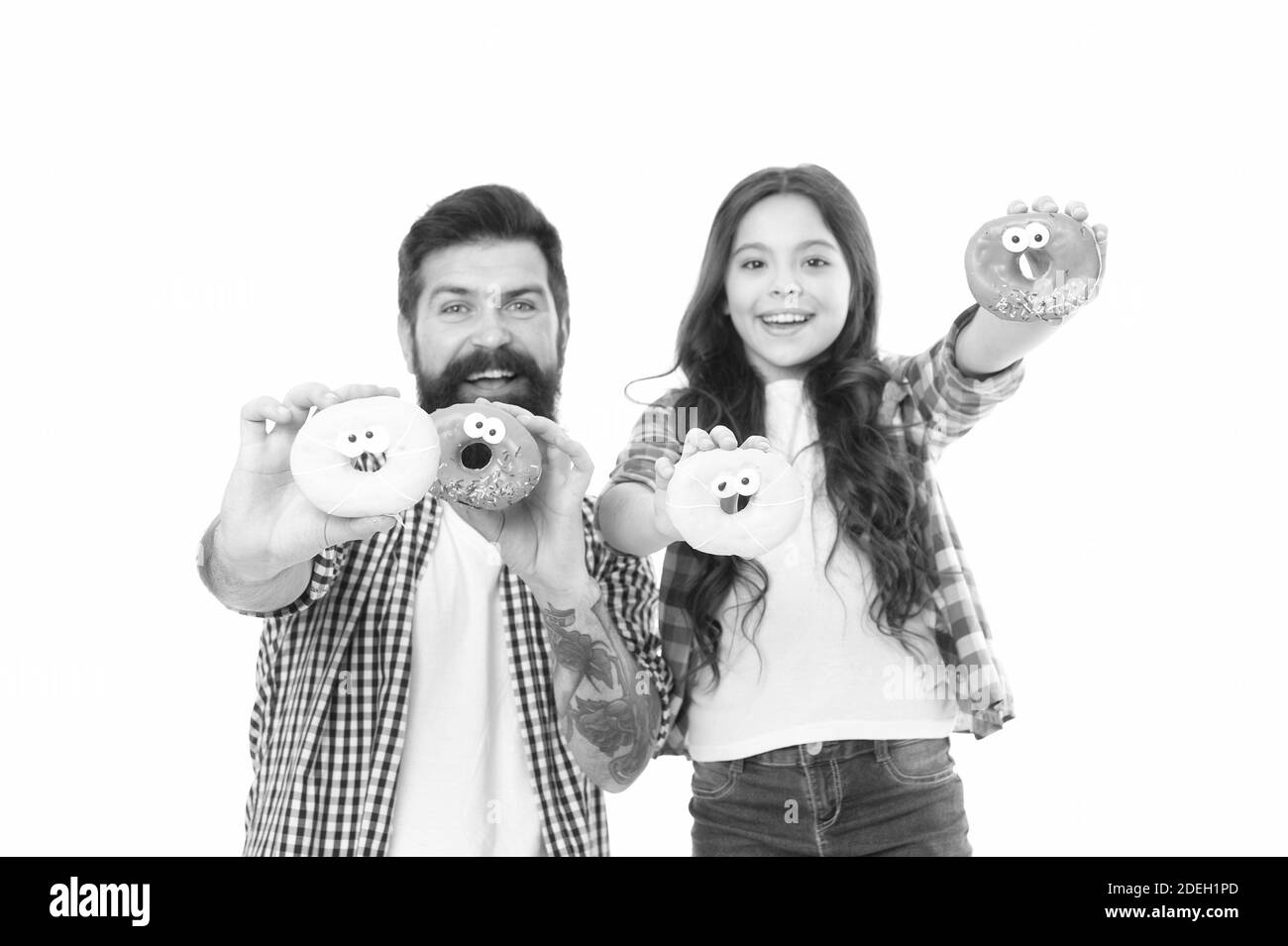 Sweet tooth. Girl child and dad hold glazed donuts. Cheerful family. Sweets and treats concept. Daughter and father eat sweet donuts. Happiness and joy. Buy more sweets. Family bakery. Bakery shop. Stock Photo