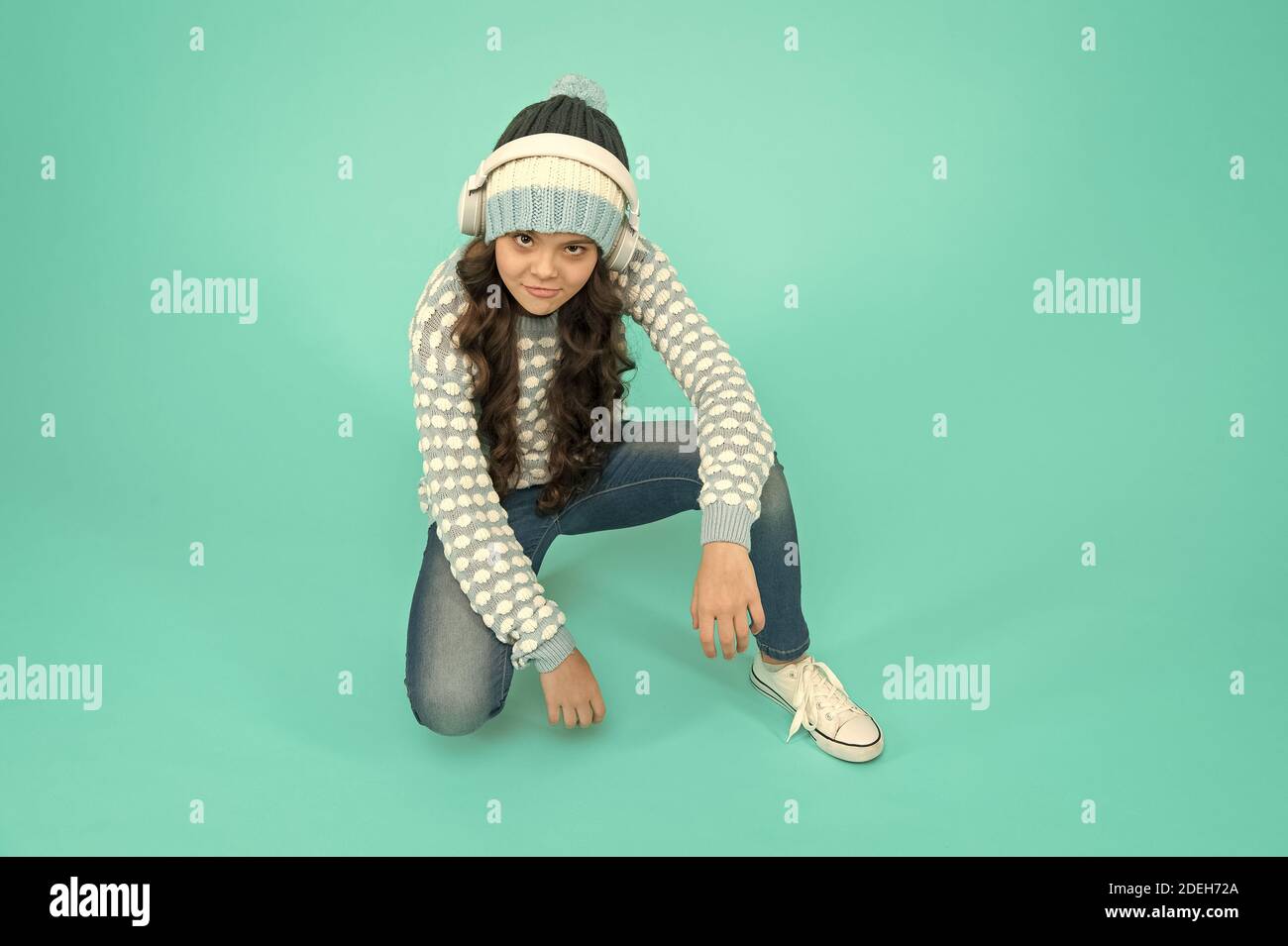 Download Cool Kid Turquoise Background Music For Winter Playlist Favorite Winter Song Girl Enjoy Favorite Tune Music Mood Small Child Knitted Sweater And Hat She Is Listening To Music On Headphones Stock Photo