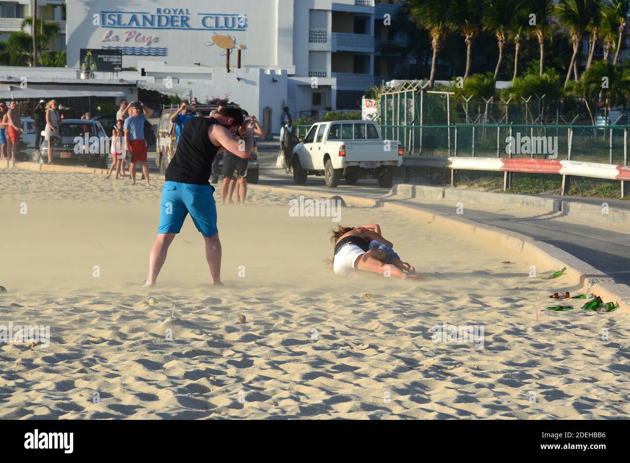 Tourists receiving jet blast at Maho Beach from departing aircraft from St. Maarten Airport in the Caribbean. Popular tourist activity. Stock Photo