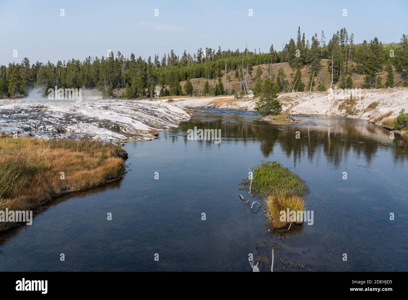 Geyserite mineral deposits from hot springs and geysers line the banks of the Firehole River in Yellowstone National Park, Wyoming, USA. Stock Photo