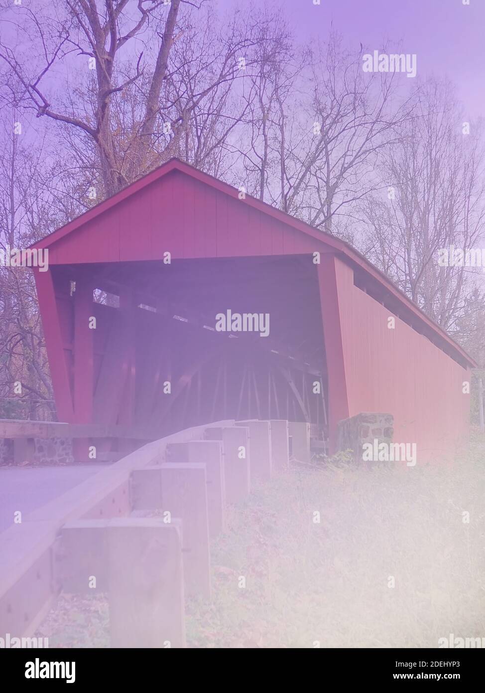 A red covered bridge with fading out foreground and purple background sky,  makes for an artistic, dreamscape, vertical  background image. Stock Photo