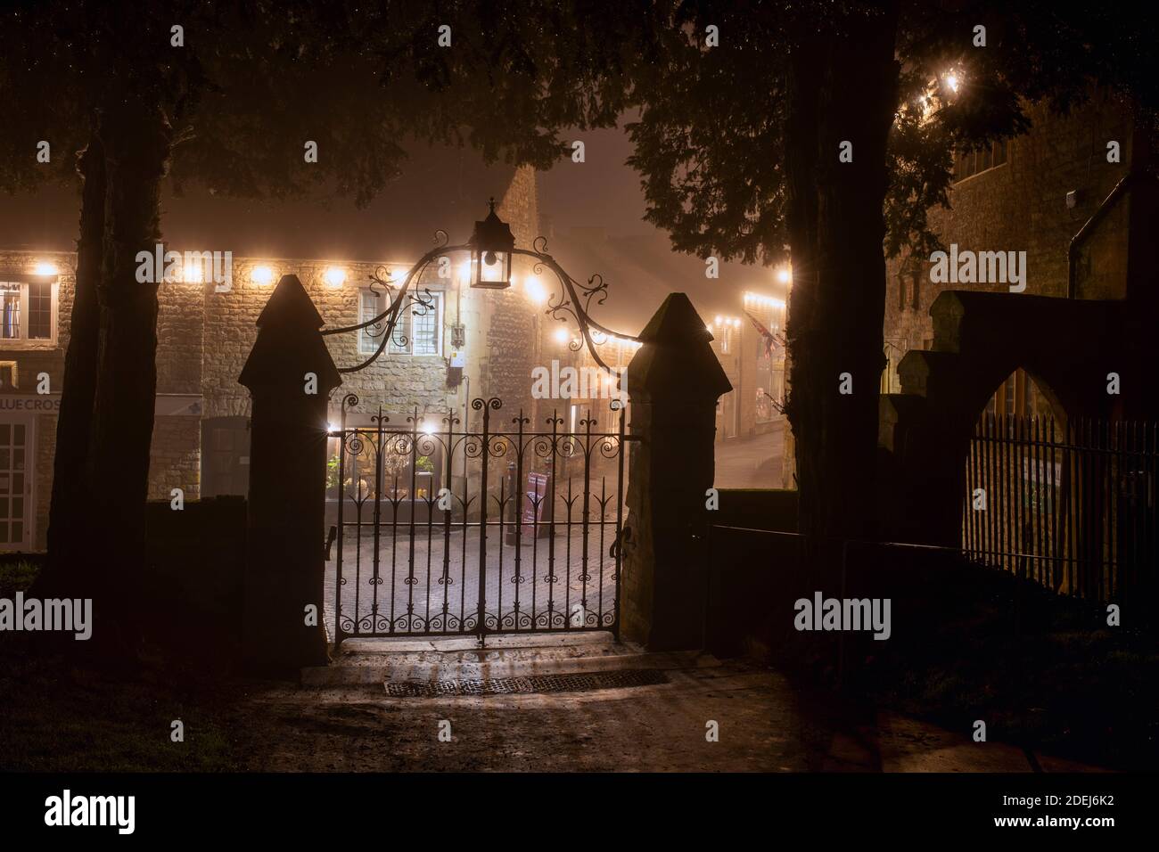 St Edwards church gates and christmas lights along church street in the mist at night. Stow on the Wold, Cotswolds, Gloucestershire, England Stock Photo