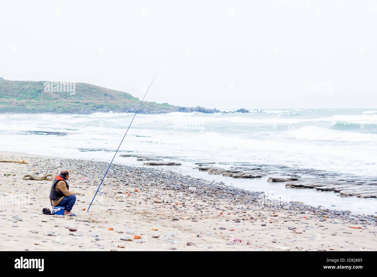 A Taiwanese man fishing at a north Taiwan beach Stock Photo