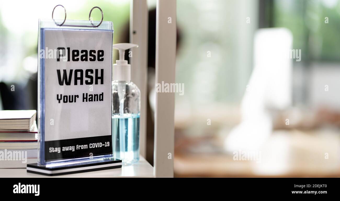 Panoramic Signage of Hand Sanitizer around office for hygiene practice after reopen with blurred background of business people working and wear face m Stock Photo