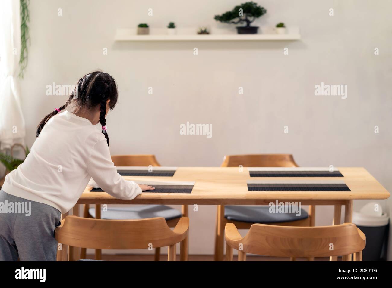 Daughter little girl setting up dining table before meal. Asian happy family doing domestic life. Stock Photo