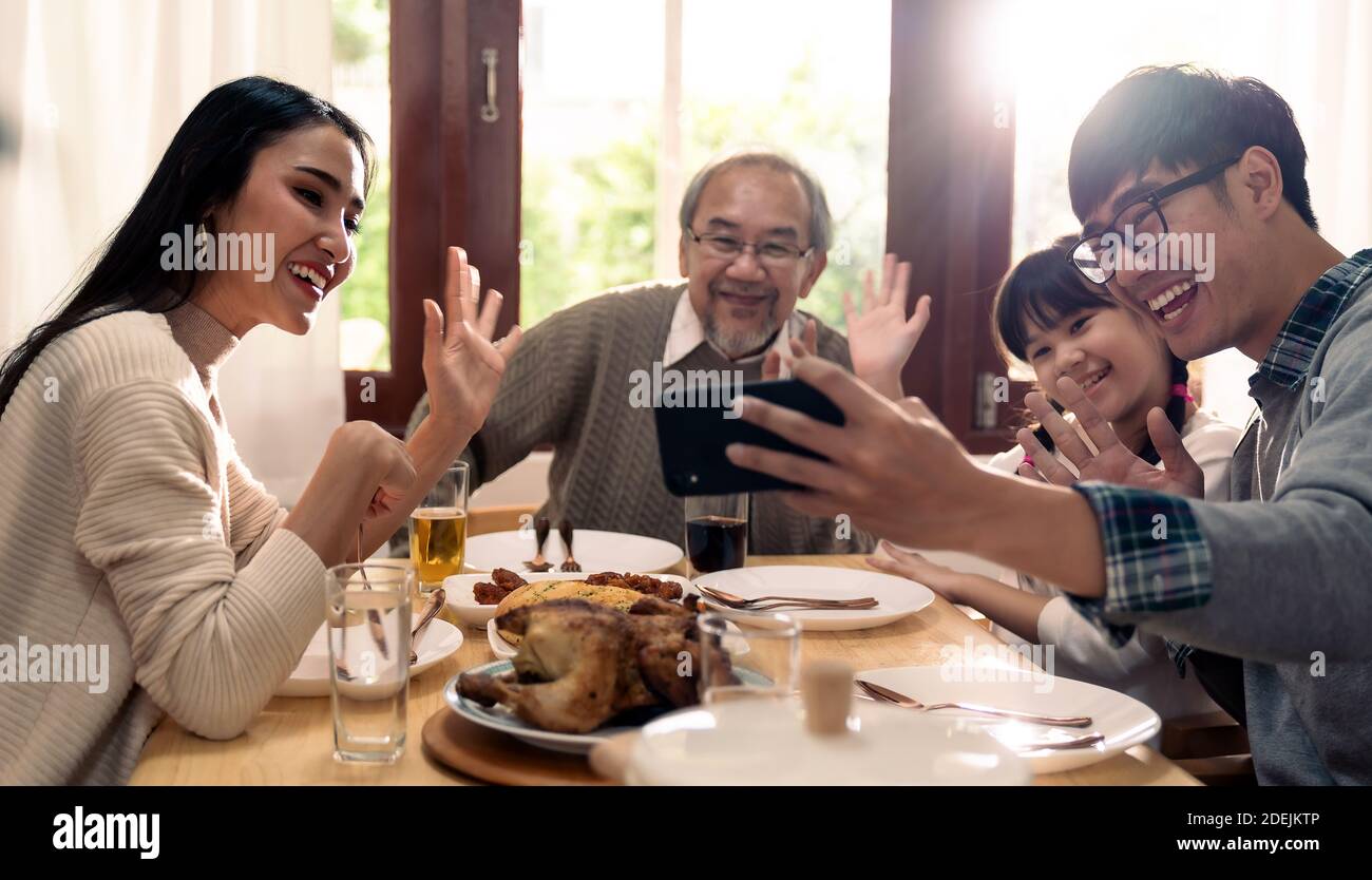 Happy asian multigenerational family of dad mom daughter girl and grandfather taking selfie together before eating lunch together at home.  Happy fami Stock Photo