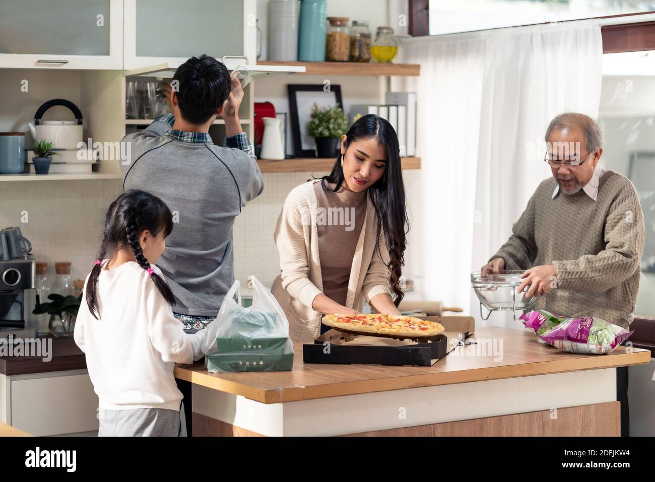 Happy asian multigenerational family of dad mom daughter girl and grandfather setting up dining table before meal. Asian happy family doing domestic l Stock Photo