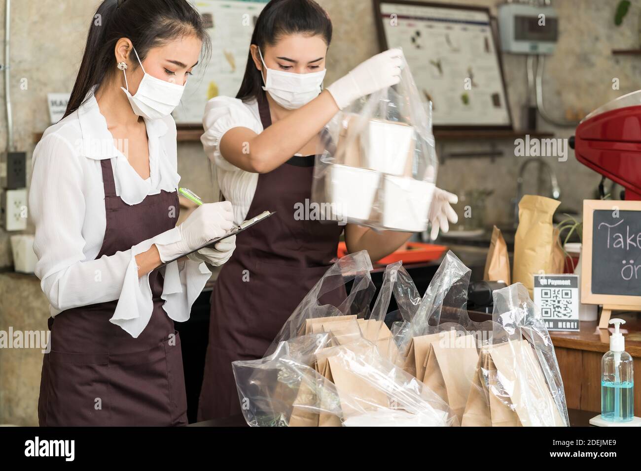 Asian waitress wear protective face mask prepare food for takeout and curbside pickup orders while city lockdown from coronavirus COVID-19 pandemic. T Stock Photo