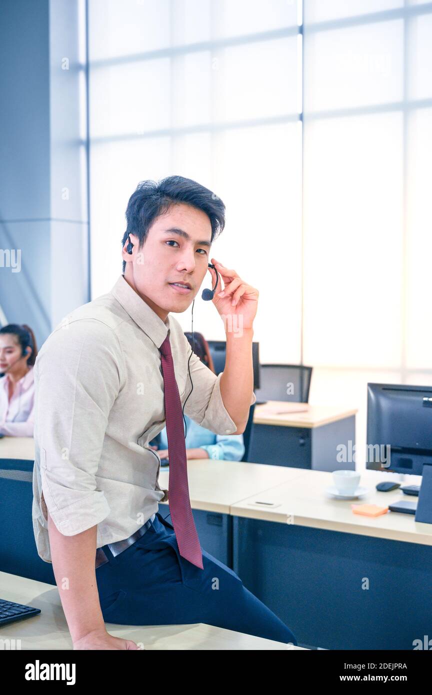 Young customer service men agent with headsets and computer working at office. Professional operator concept. Stock Photo