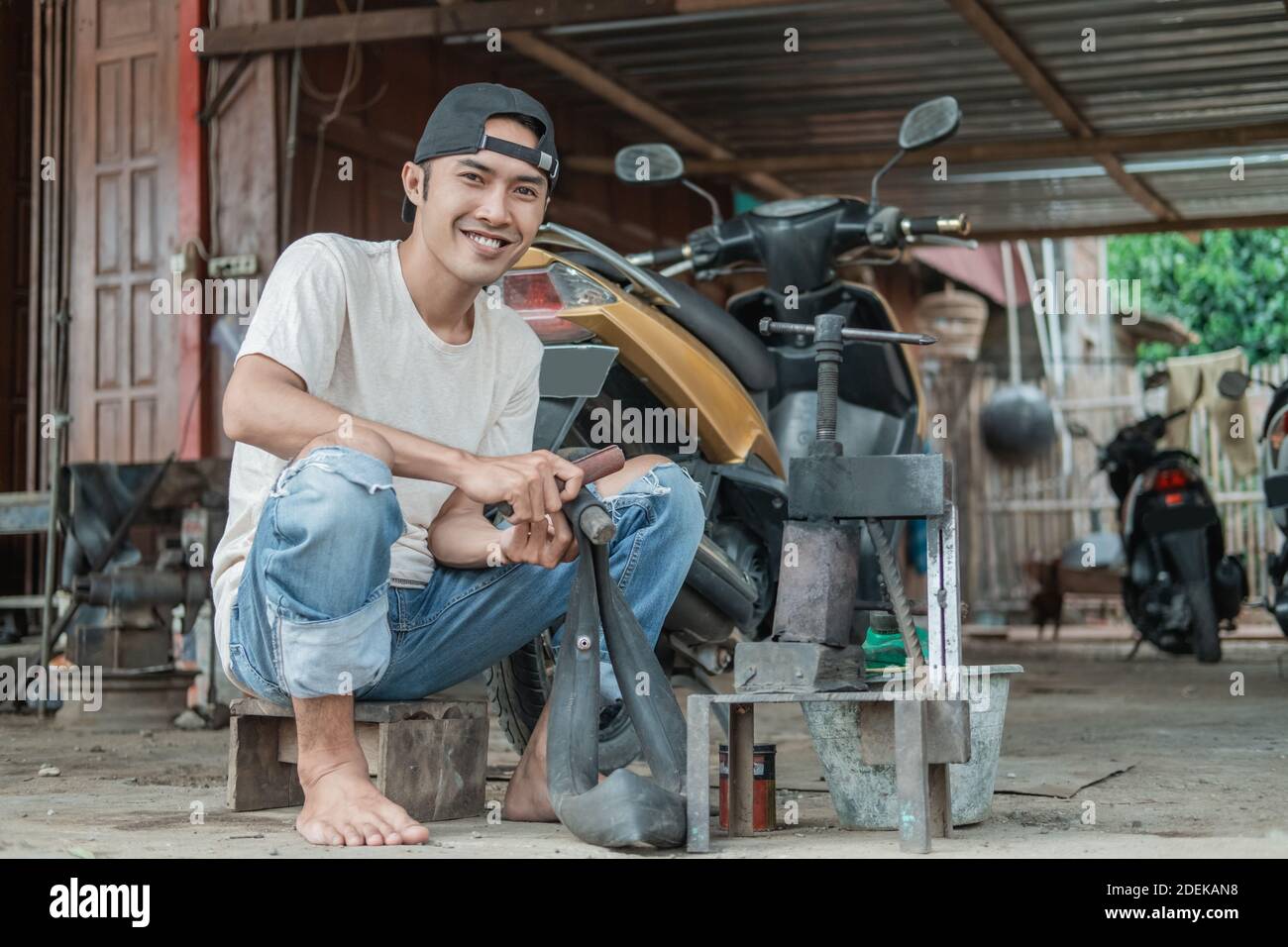 smiling tire patcher sits rubbing a leaky inner tube in a motorcycle
