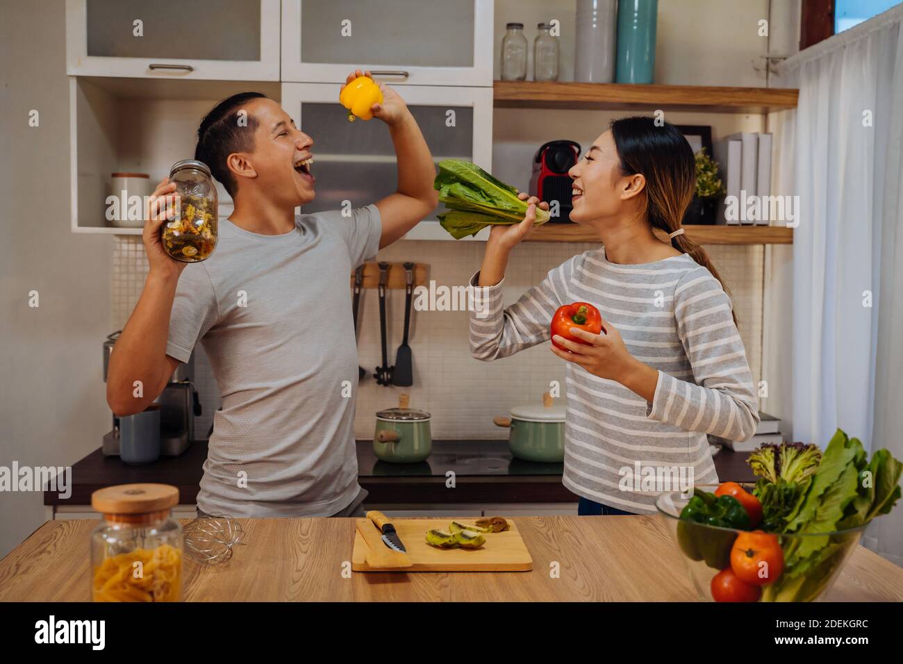 Young lovely couple dancing in the kitchen with window. Asian woman and