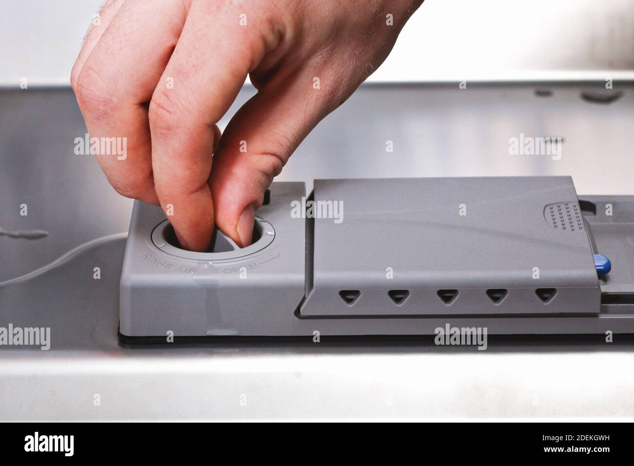 A man pours a rinse aid into the dishwasher compartment Stock Photo - Alamy