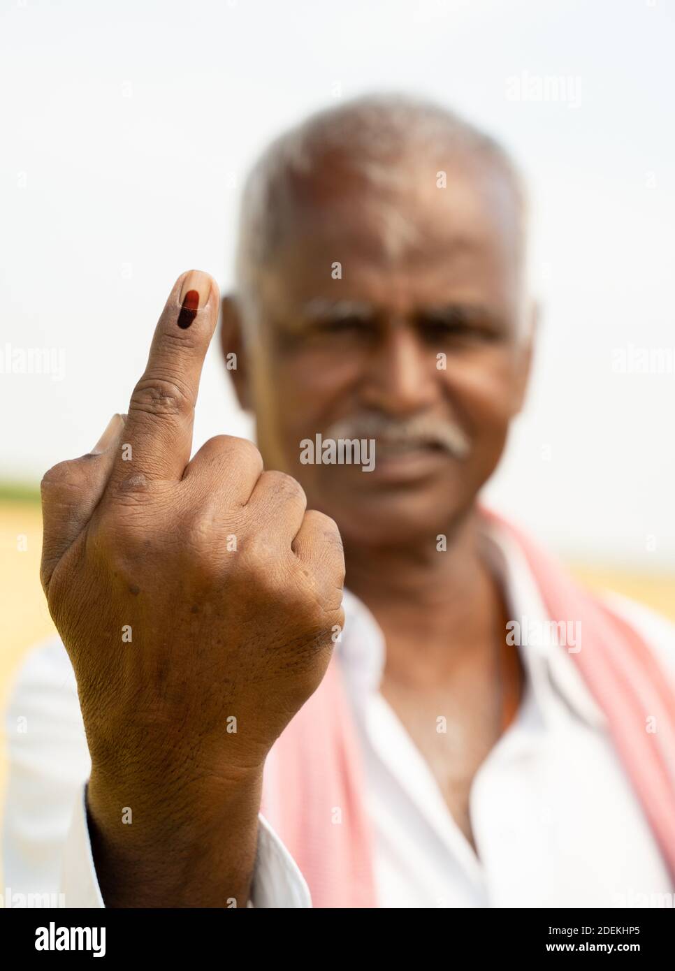 Selective focus on hand, Indian farmer showing ink marked finger after voting during Indian election in hot sunny day new agriculture farmaland. Stock Photo