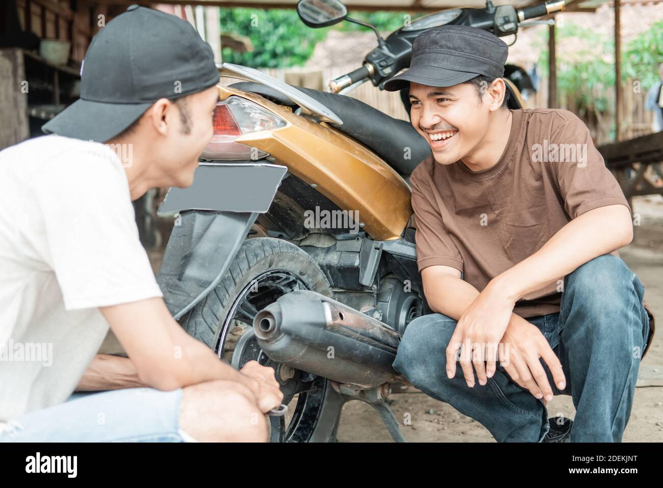 Asian man smiles at a tire repairman after fixing a leaky motorbike