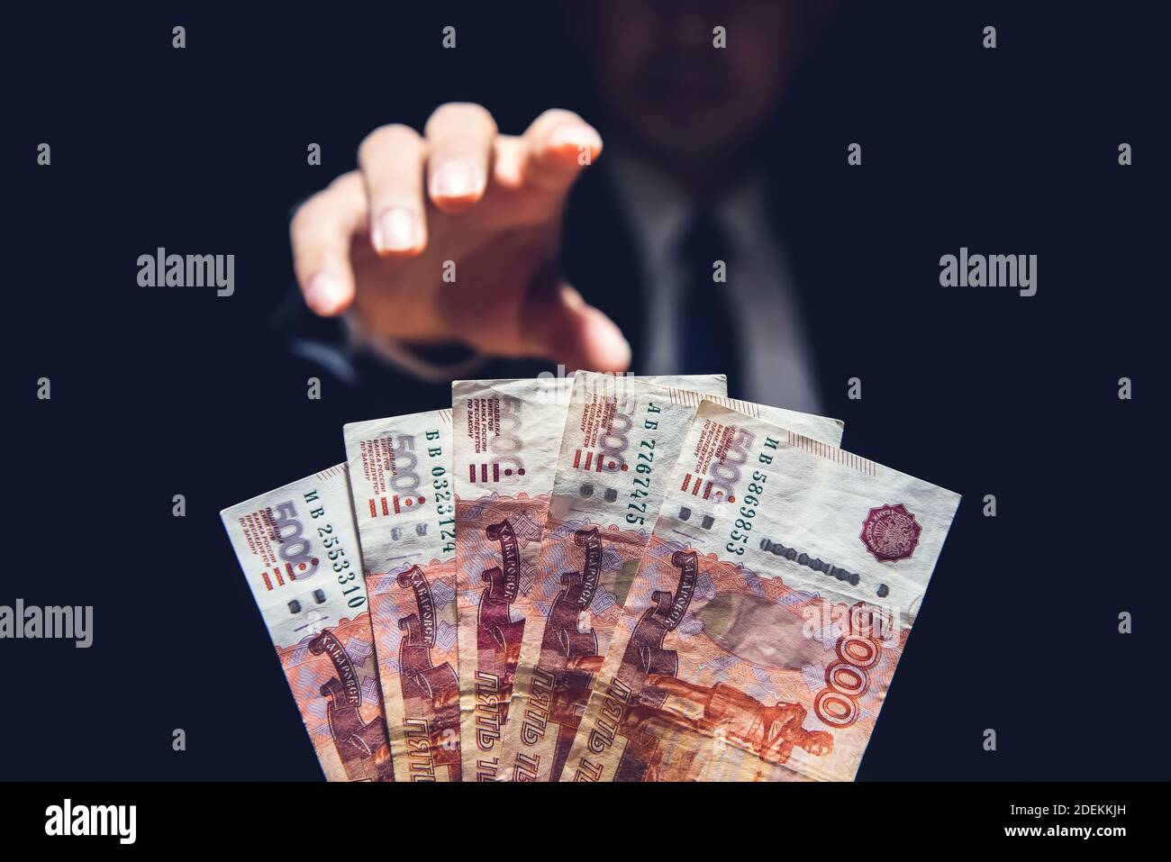Anonymous businessman reaching out hand to grab money, Russian ruble currency, in dark room Stock Photo